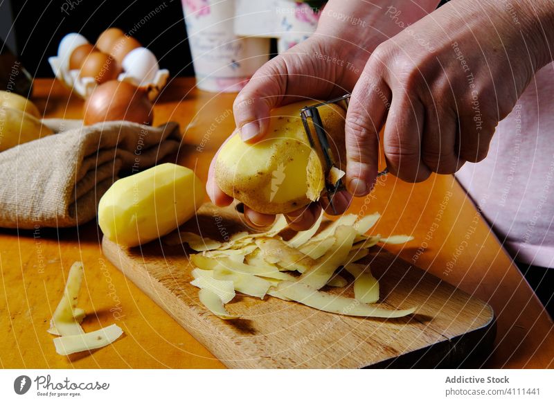 Unrecognizable chef peeling potato in kitchen cook hand food fresh yellow organic healthy wooden natural table prepare knife slice raw equipment home vitamin