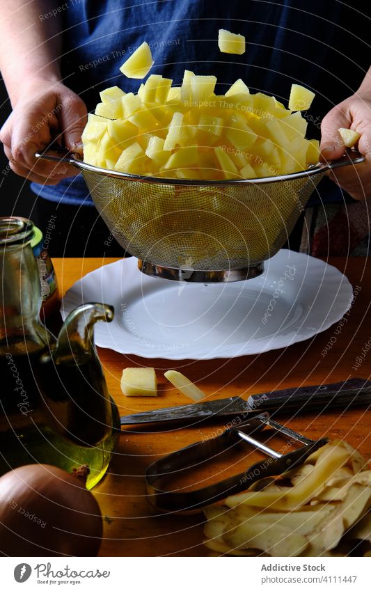 Anonymous woman preparing pieces of potatoes for dish with sieve chef cook prepare process slice fresh food kitchen homemade ingredient organic raw recipe table