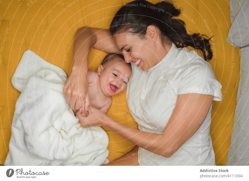 Overjoyed mother lying with baby laugh smile together enjoy child adorable little kid innocent cute happy love parent affection rest bed comfort embrace bonding