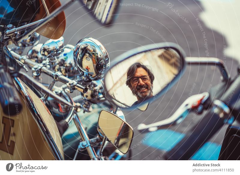 Reflection of male in motorcycle mirror reflection man street smile city transport mature biker vehicle travel lifestyle journey joy relax rest classic retro