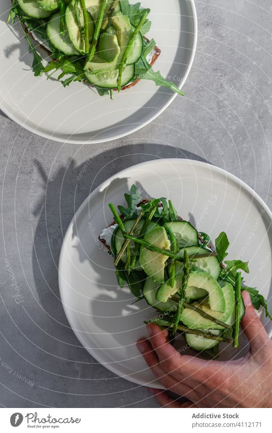 Person holding toast with green vegetables healthy vegetarian natural fresh herb food hand person bread sandwich avocado cucumber meal delicious tasty lunch