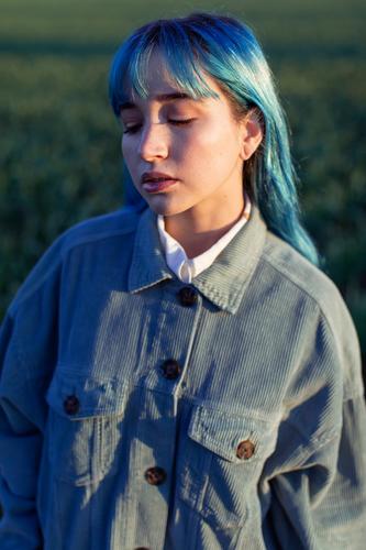 Sad stylish woman standing in field trendy melancholy pensive sad informal dyed hair alone hipster blue hair style fashion calm sunlight young meadow evening