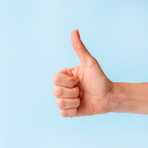 Closeup of female hand showing thumbs up sign against pastel blue background, copy space, minimal concept woman finger symbol business arm good person positive