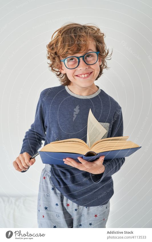 blond kid in pajamas with a book playing research children game protect happiness enjoyment room indoor party comfort emotional expression kids joyful