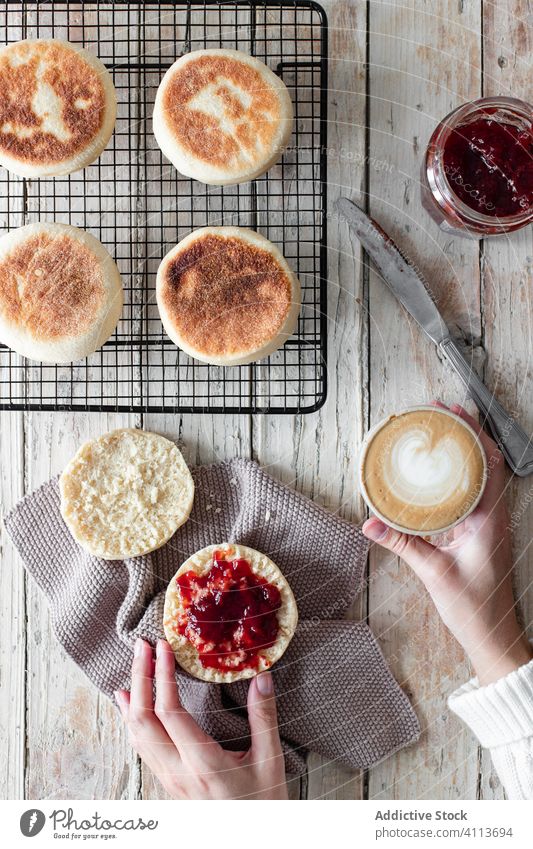 Woman having breakfast with cappuccino and homemade bun jam food fresh bake table hand delicious tasty pastry dessert sweet yummy berry nutrition morning wooden