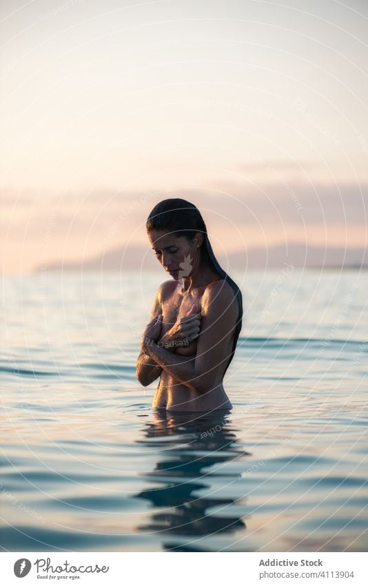 Naked woman in sea during sunset nude nature cover breast wet evening water female ocean relax vacation summer harmony calm slim weekend sensual lady seductive