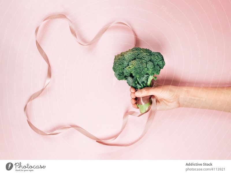 Crop person with healthy broccoli and pink ribbon diet show organic concept fresh food vegetable vegetarian vitamin vegan veggie green raw meal silk grace