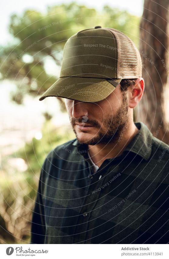 Man in checkered shirt and baseball cap in forest handsome male portrait casual man attractive hat adult person style thoughtful caucasian confident modern