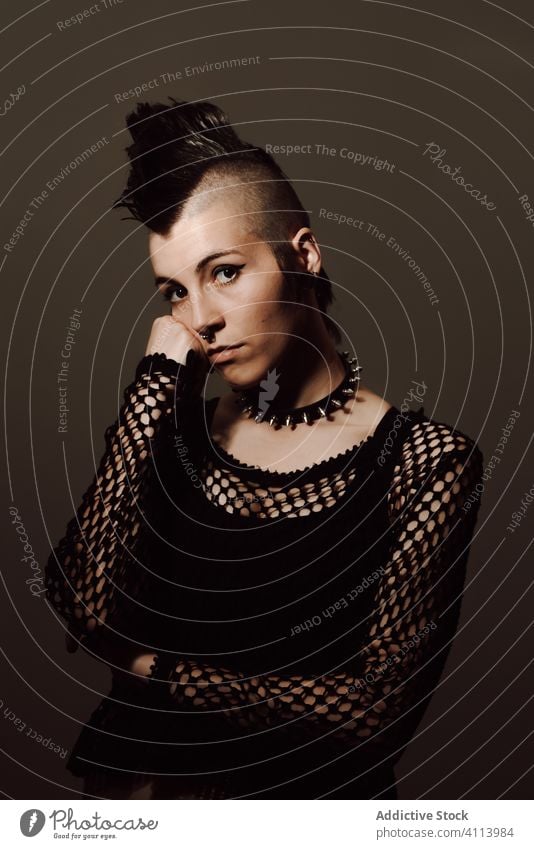 Confident female punk looking at camera woman style confident subculture modern rebel mohawk appearance dark model piercing individuality personality