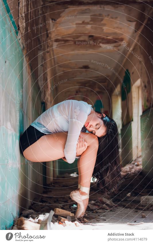 Young ballerina dancing in grungy corridor woman dance ballet grace concept grunge abandoned embracing knee young slim female elegant eyes closed demolish