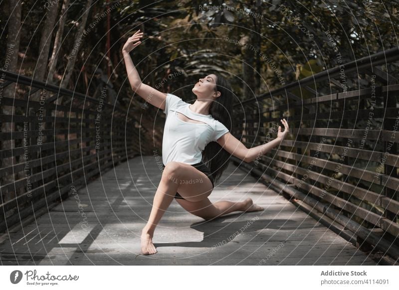 Barefoot woman dancing on bridge in garden dance grace concept young eyes closed barefoot slim female elegant outstretch ballerina park calm tranquil serene