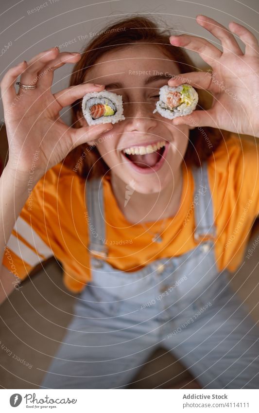 Young woman playing with sushi fun happy eye home lunch japanese young tasty female rice seafood roll smile excited dinner dish meal cheerful snack fresh lady