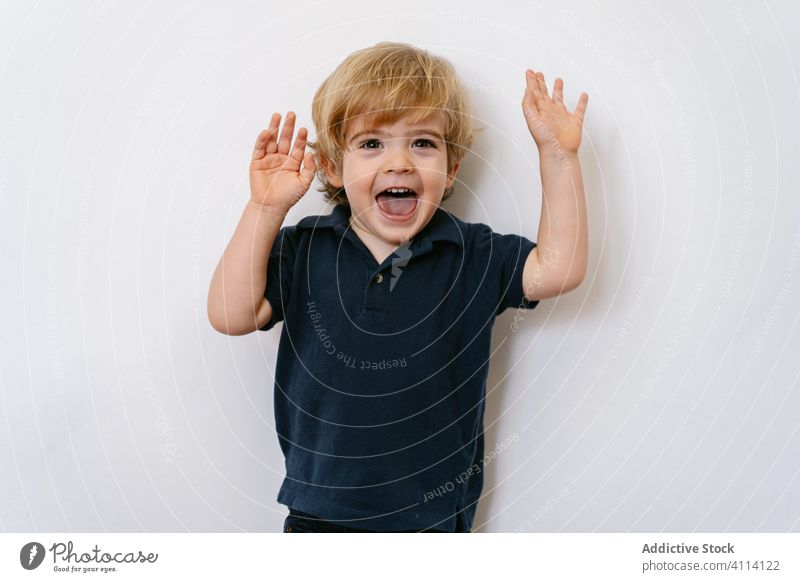 Cheerful little kid showing fingers while raising hands up cheerful laugh wow game expressive happy hand raised boy energy hand up preschool adorable ready