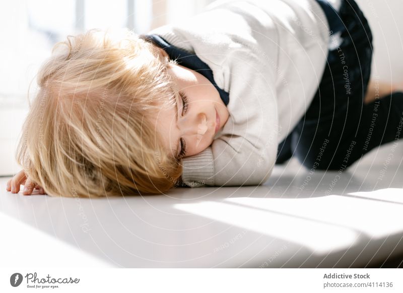 Pensive little boy lying on window sill lazy bored charming home alone sunlight calm kid child pensive girl asleep rest sunny blond day relax lifestyle