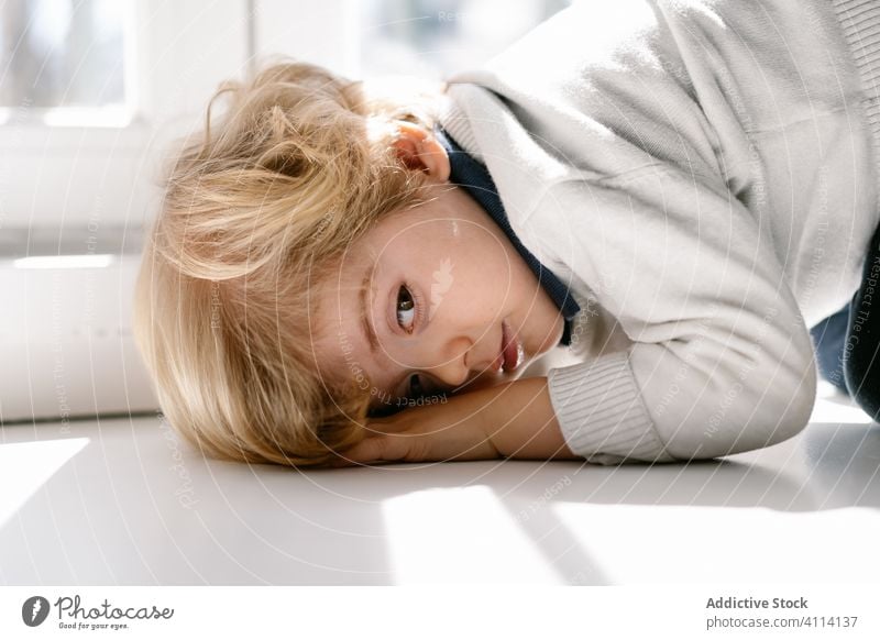 Pensive little boy lying on window sill lazy bored charming home alone sunlight calm kid child pensive girl rest sunny blond day relax lifestyle childhood cozy