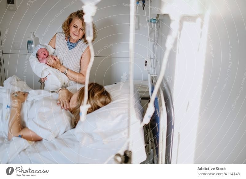 Woman visiting daughter with newborn baby in hospital mother grandmother women care bed greeting clinic happy neonatal kid medicine parent multi generational