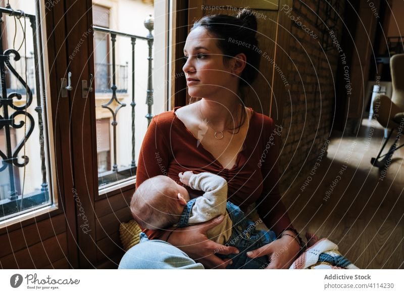 Happy mother breastfeeding baby near window home happy love rest cozy sit woman cute room hug embrace smile child kid childhood little care together parent