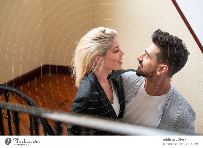 Loving couple hugging on staircase love home smile diverse relationship man woman together stairway step embrace happy cheerful romantic lifestyle multiethnic
