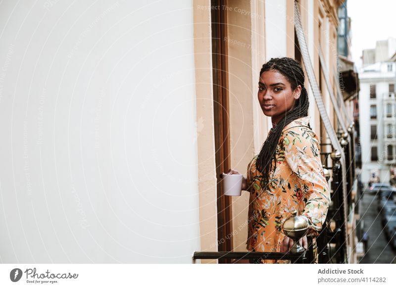 Young woman with cup of coffee standing on balcony calm drink casual home tranquil thoughtful relax young african american black ethnic brunette house city