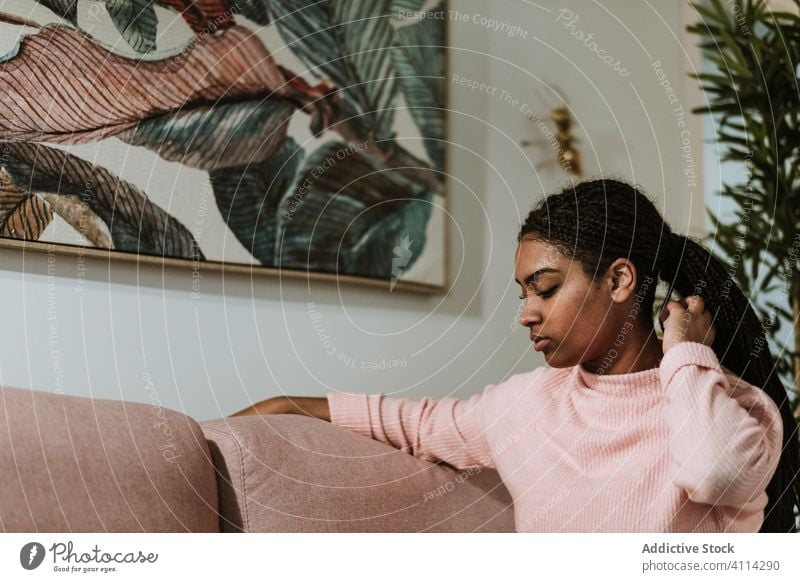 Bored young woman sitting on sofa home thoughtful bored casual rest pensive african american black ethnic couch relax lazy calm sad cozy peaceful think serious