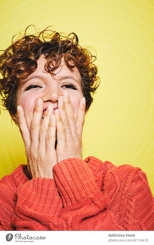 Excited woman in warm sweater in studio amazed laugh happy surprise cheerful excited style trendy knitted curly hair joy casual glad expressive vibrant vivid