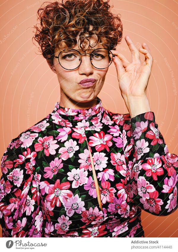 Doubtful woman in trendy outfit fashion style doubt thoughtful eyeglasses colorful floral young female model pensive cloth accessory eyewear curly hair vintage