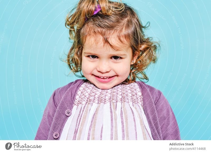 Happy little girl with cute toothy smile in studio preschool happy kid cardigan dress innocent woman positive style joy charming child appearance female