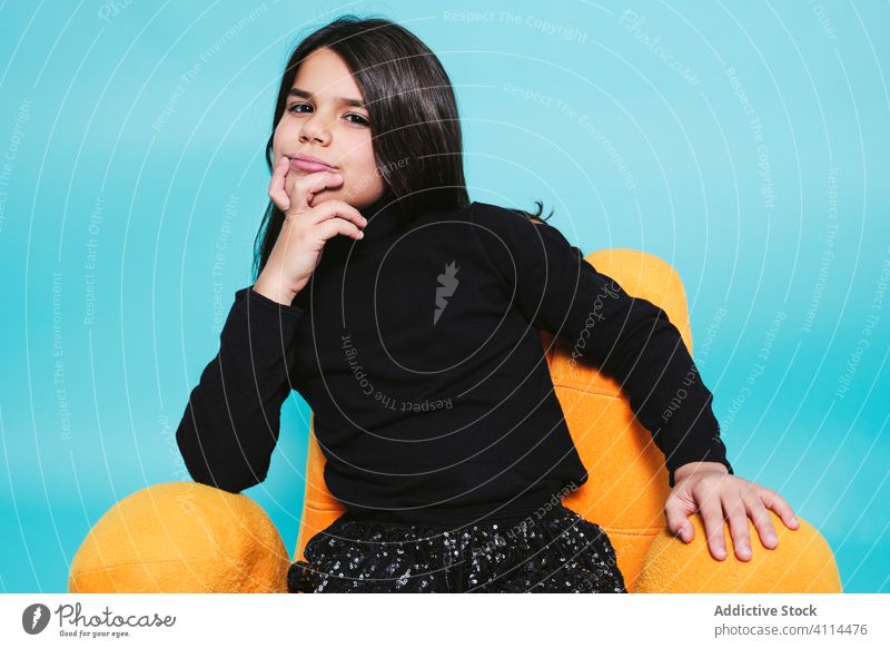 Young woman in funny colorful armchair in studio girl relax brunette preteen joy lounge confident chill smile child carefree kid soft female hand childhood