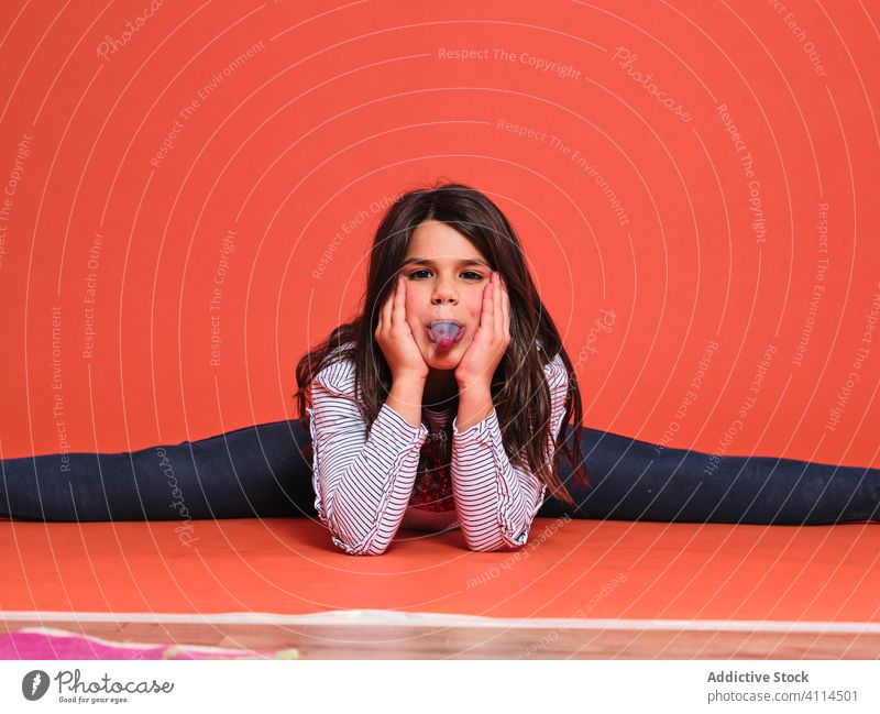 Cheerful girl doing splits in bright studio kid happy cheerful trendy joy smile colorful positive female casual vivid expressive brunette glad excited gymnast