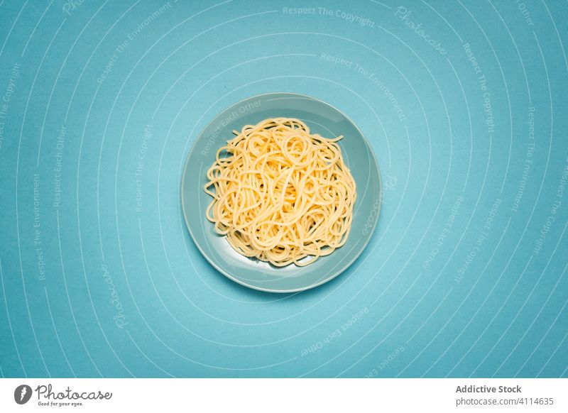 Delicious spaghetti on blue background delicious ceramic italian simple plain heap cooked wooden table plate pasta tasty healthy dinner dish gourmet tradition