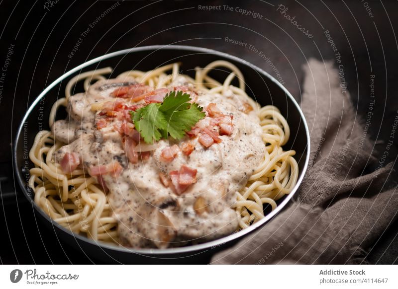 Top view of appetizing pasta with ham and mushrooms in creamy sauce served in frying pan tasty spaghetti cutting board healthy food meal gourmet delicious