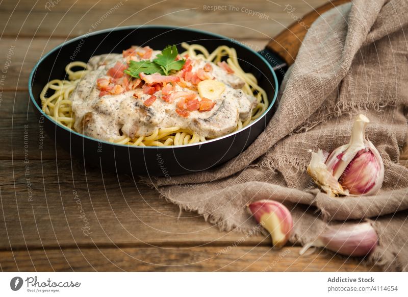 Pasta with ham and mushrooms in creamy sauce served in frying pan pasta tasty spaghetti cutting board healthy food appetizing meal gourmet delicious cuisine