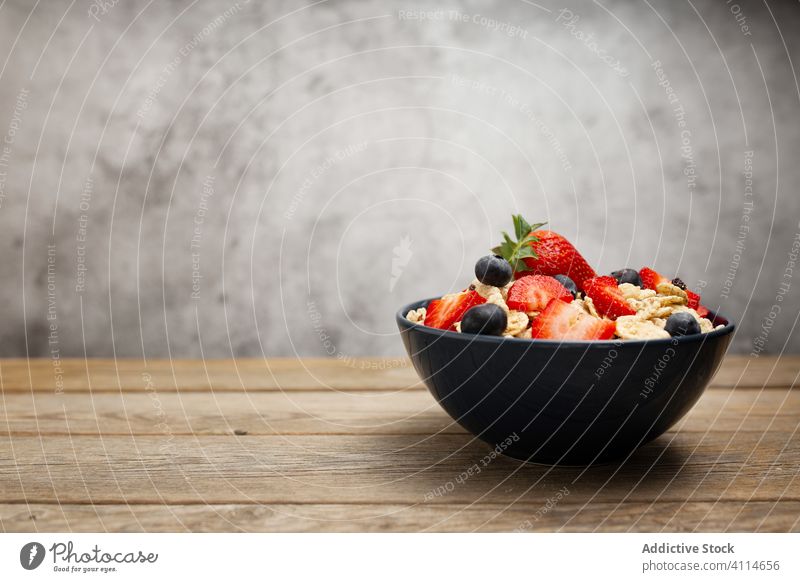 Fresh cornflakes served with strawberries and blueberries placed on wooden table breakfast strawberry blueberry cereal delicious fresh bowl organic healthy