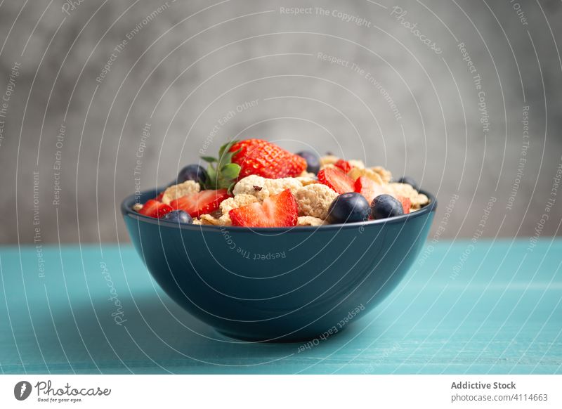 Fresh cornflakes served with strawberries and blueberries placed on blue wooden table breakfast strawberry blueberry cereal delicious fresh bowl organic healthy