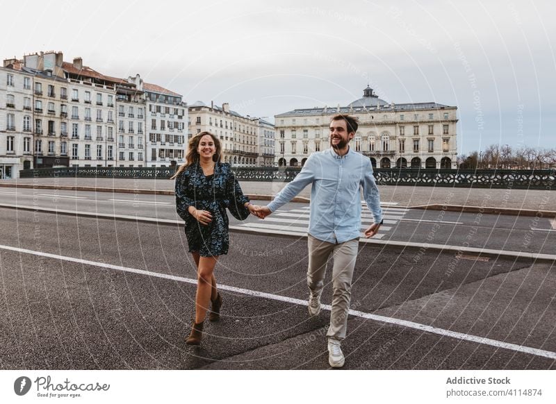 Cheerful couple crossing street in city together travel historic square bridge road walk happy love relationship romantic boyfriend girlfriend affection