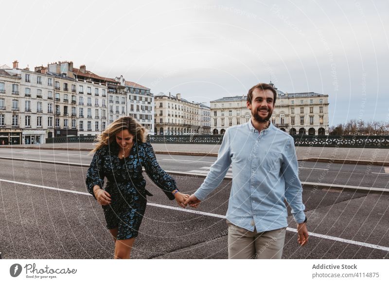 Cheerful couple crossing street in city together travel historic square bridge road walk happy love relationship romantic boyfriend girlfriend affection