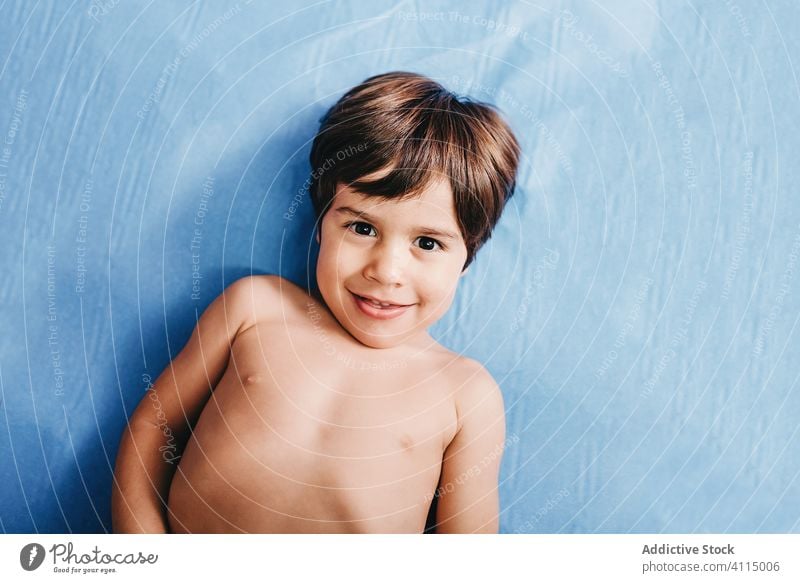 Happy kid lying on blue bed in clinic happy smile hospital shirtless patient little boy cheerful child childhood health care joy healthy cute male positive