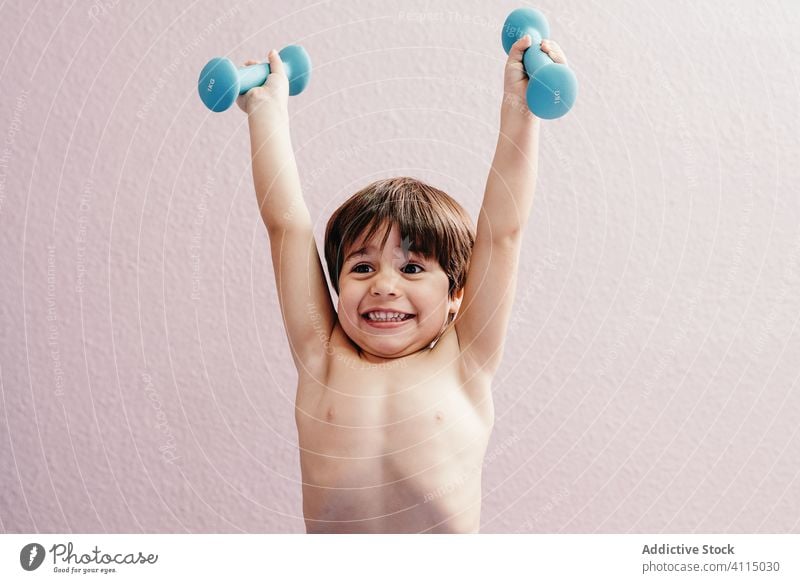 Cheerful little boy with dumbbells kid healthy happy active smile cheerful energy positive child exercise lifestyle joy training childhood glad health care