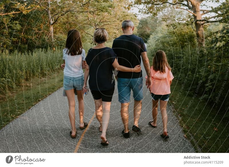 Happy family walking in nature in summer day together park forest countryside path active casual green pathway love relationship lifestyle tree bonding vacation