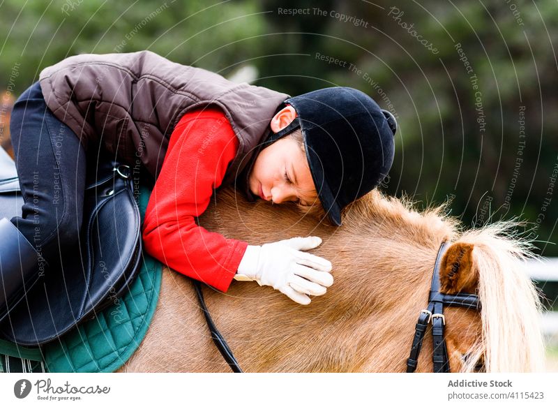 Kid hugging pony in paddock kid equestrian jockey school lesson love friend saddle sit child mane horseback animal helmet embrace ride sport training education