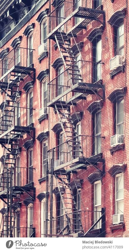 New York old building with fire escape, color toning applied, USA. city Manhattan retro vintage townhouse filtered architecture stairs apartment facade NYC