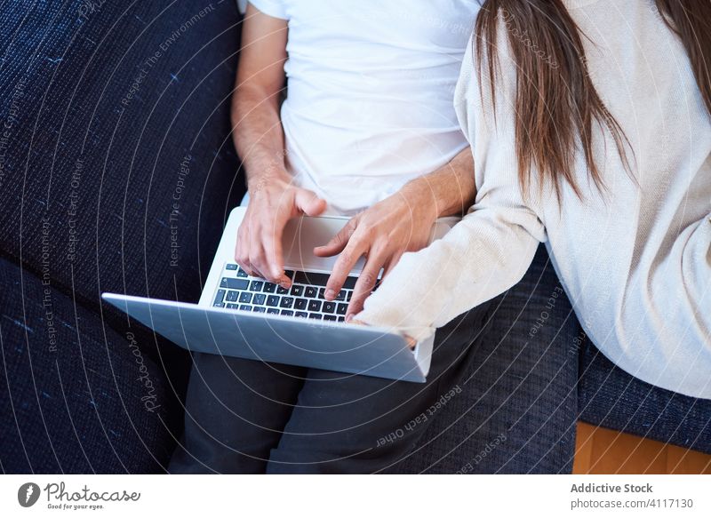 Young couple resting on cozy sofa at home together laptop using read young relationship husband couch device gadget online internet calm tranquil fondness