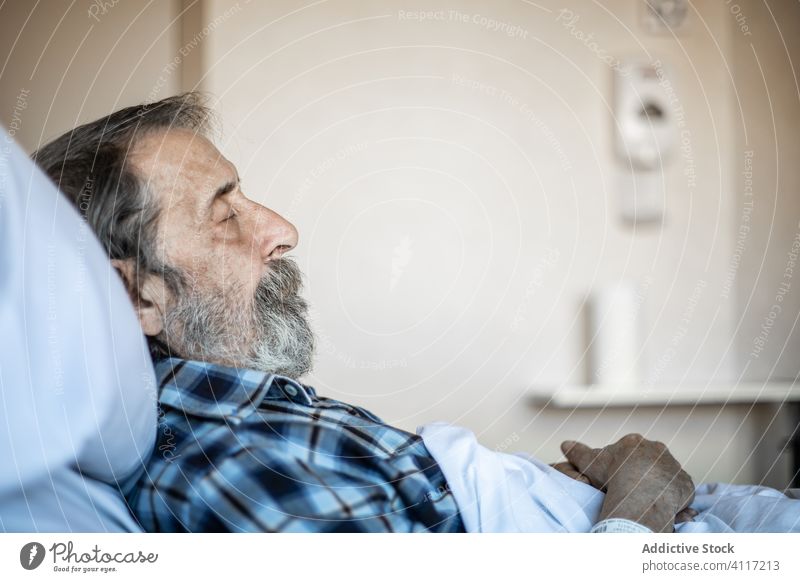 Senior man sleeping in hospital bed senior ward elderly patient medicine illness tired clinic old blanket recovery disease control age unwell problem