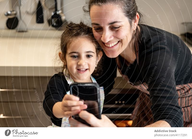 Mother taking selfie with kid during pastry preparation mother children cook home kitchen smartphone mobile phone smile happy love together cozy girl woman