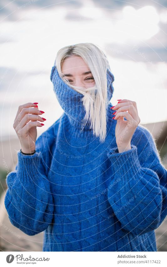 Cheerful young woman in warm sweater blue happy sea laugh positive blonde joy female nature cheerful style warm clothes knitted millennial holiday charming