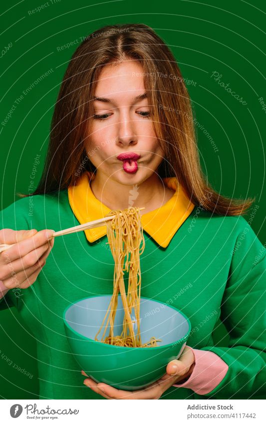 Happy young woman eating noodles instant color happy yummy hungry positive female chopstick bowl food smile delicious tasty expressive delight enjoy fast food