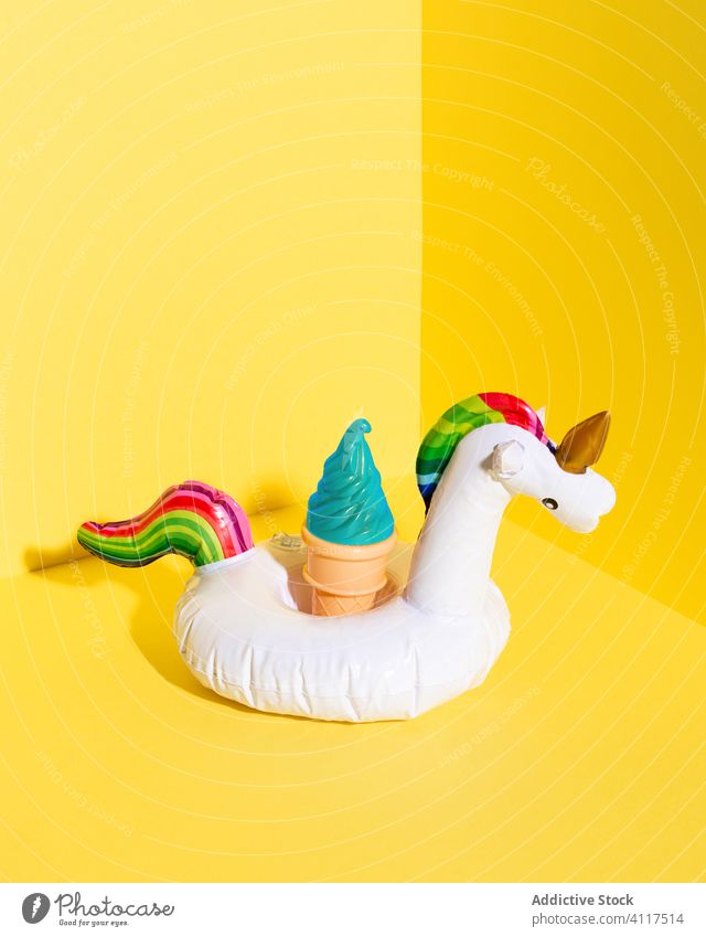 Colorful summer pool toys on yellow background ice cream unicorn inflatable colorful cone concept vibrant bright artificial vacation holiday composition plastic