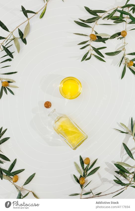 Olive branches and oil on white table olive glass natural healthy ingredient organic food nutrition plant leaf diet jar fresh vegetarian meal cuisine tree