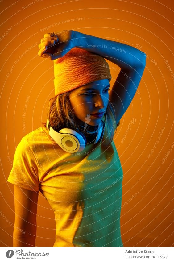 Woman model with headphones around the neck woman style modern illuminate bright hands behind head young female accessory hat t shirt hipster confident headgear