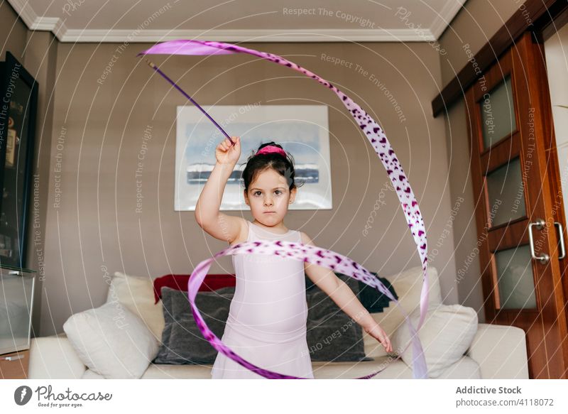Little gymnast exercising with ribbon at home girl gymnastic dance rehearsal rhythmic spin training little leotard living room child dancer childhood perform
